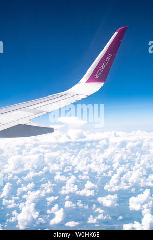 Wizzair logotipo o marca en la aleta, el cielo azul con las nubes desde el avión ver Foto de stock