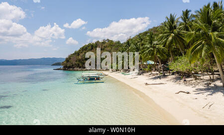 Impresionante paisaje tropical en las Filipinas. Filipino tradicional Lancha estacionada en un soñado playa con palmeras, arena blanca y el agua azul
