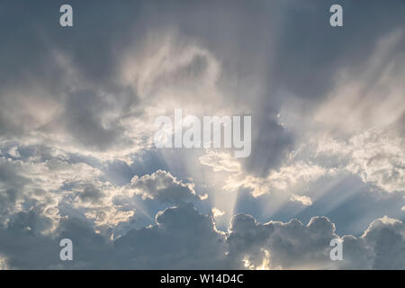 Cielo dramático como nubes oscuras parcialmente la luz del sol provocando rayos crepusculares en el cielo nocturno Foto de stock