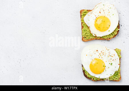 Tostadas con puré de aguacate y sunny side up huevo en hormigón gris de fondo. Vista superior de la tabla, alimentos saludables, comer limpio concepto