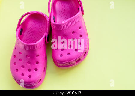 San Diego, Estados Unidos, 10 de mayo de 2019.El verano rosa flip flops aislado sobre fondo amarillo. niños sandalias de goma blanda o Crocs.vacaciones de verano zapatos de de stock -