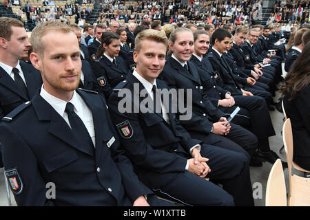 04 de julio de 2019, el Schleswig-Holstein, Neumünster: policías jóvenes están sentados en el Holstenhallen en la ceremonia de despedida de 250 futuros comisarios del curso de licenciatura en la aplicación de la Ley de policía. La toma de juramento de los nuevos policías tendrá lugar en septiembre. Foto: Carsten Rehder/dpa Foto de stock