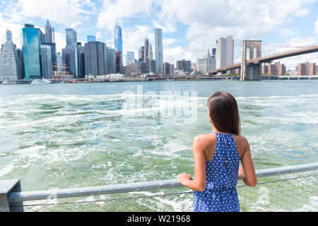 Mujer urbana de la ciudad de Nueva York disfrutando de vistas del centro de la ciudad de Manhattan desde Brooklyn Park, viviendo una vida feliz caminar durante el viaje de verano en EE.UU. Turismo Asiático Femenino en su 20s.