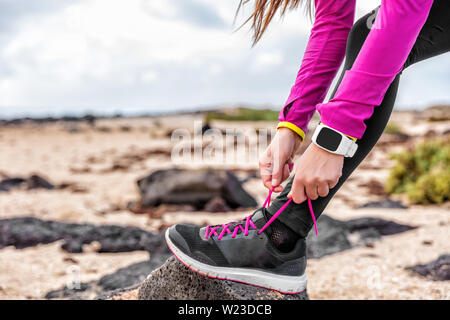 Smartwatch Fitness mujer runner zapatillas costura en Playa Chica, un atleta preparándose para ejecutar entrenamiento Running Shoe Cordones de atado fuera vistiendo watch marcha. Concepto estilo de vida saludable Fotografía