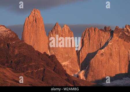 Luz solar naranja al amanecer sobre las Torres en el Parque Nacional Torres del Paine, Magallanes, Patagonia Chilena.