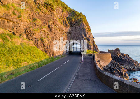 Arco negro túnel y Causeway Ruta Costera. Carretera Escénica a lo largo de la costa oriental del Condado de Antrim, Irlanda del Norte, Reino Unido. Vista aérea de la luz del amanecer