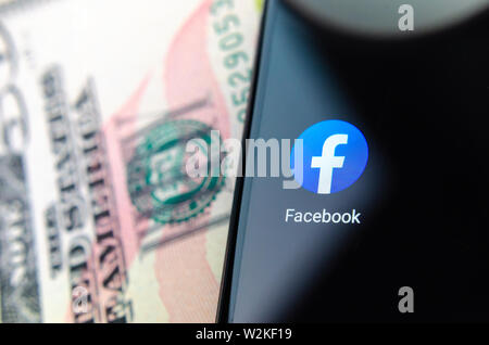 Facebook app icono junto al símbolo de la reserva federal 50 billetes de dólar. Ilustrar las Noticias sobre Facebook el lanzamiento de su propia moneda libra. Foto de stock