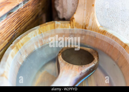 Primer plano de una cuchara de madera en el balde con agua por la sauna de estilo japonés tradicional Foto de stock