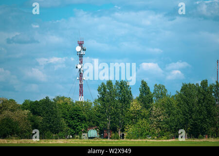 Torre de comunicaciones militares con diversos equipos de comunicaciones y antenas de radio y 5G dentro de un bosque Foto de stock