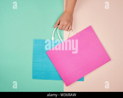 Mano sosteniendo dos bolsas de papel sobre un fondo de color pastel, el  concepto de ventas de temporada Fotografía de stock - Alamy