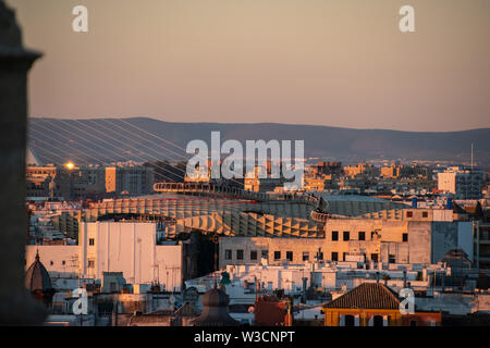 Una vista de la ciudad española de Sevilla durante una puesta de sol naranja con el Metropol Parasol llegando a través de los edificios