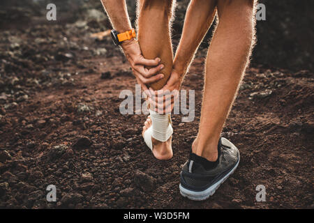 Hombres runner mantiene heridas músculo de la pantorrilla de cerca el dolor y el sufrimiento. Herida en la pierna. Vendaje de compresión en el tobillo. Vista desde atrás. Esguince del ligamento o Foto de stock