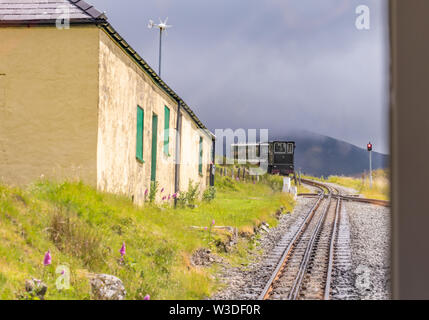 Tren de vapor que llegó a casa de medio camino en su cruce hacia adentro enlazado viaje desde la cumbre del monte Snowdon en el monte Snowdon Railway Line Foto de stock