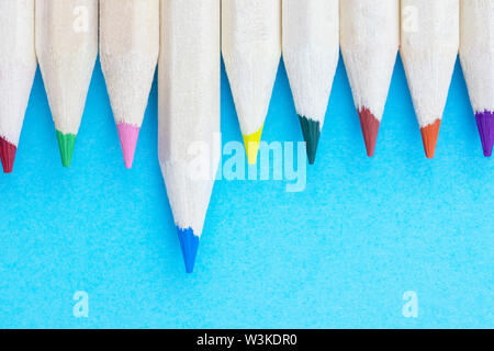 Lápices multicolor sobre fondo azul , lápices de madera con puntos de color en una fila ,Foto de estudio