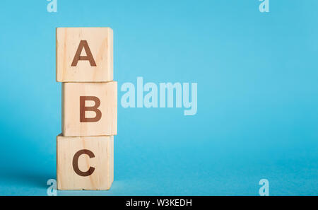 ABC letras de bloques de madera en forma pilar sobre fondo azul. Foto de stock