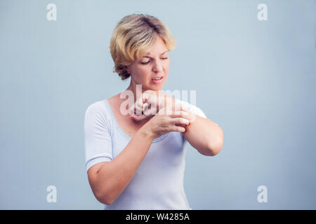 Mujer rascarse una picazón sobre fondo blanco . Piel sensible, los síntomas de la alergia alimentaria, la irritación Foto de stock