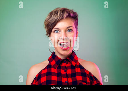 Personas y emociones - sonriente joven mujer con cabello oscuro corto muestra su lengua Foto de stock