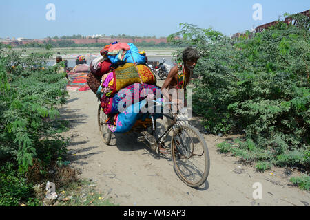 Agra, India - Jul 13, 2015. Un viejo hombre llevando ropa en bicicleta en los bancos de arena del río Yamuna, Agra, India. Agra tiene tres UNESCO World Herita Foto de stock
