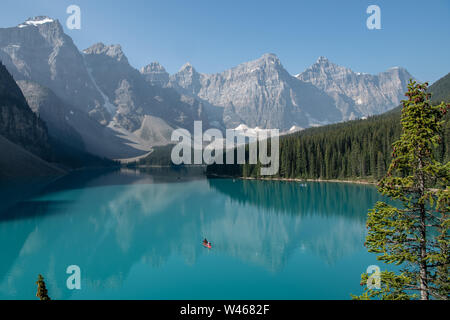 Montañas reflejadas en las aguas verde esmeralda del lago Moraine, Alberta, Canadá Foto de stock