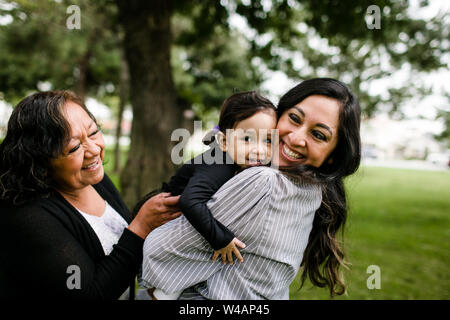Abuela, madre e hija, abrazarse y reír en el parque