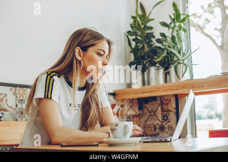 Mujer joven con el portátil en el cafe Foto de stock