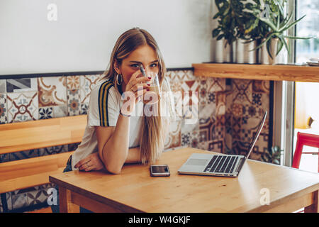 Mujer joven bebiendo café en el café