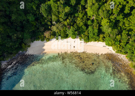 Antena drone vista de una playa pequeña en una exuberante isla tropical (Isla de la caverna) Foto de stock