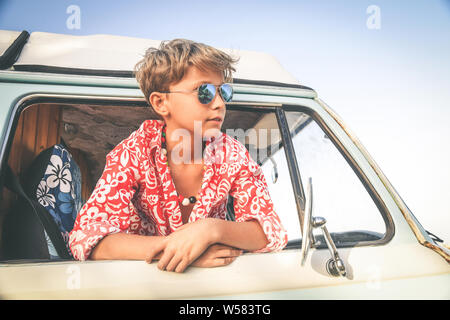 Vista inferior del guapo muchacho encantador posando con gafas de sol por la ventana de la vendimia van vestidas como flor hippie niño concepto de libertad y de li Foto de stock