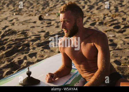 Retrato del hombre que confía con tablas de surf en la playa