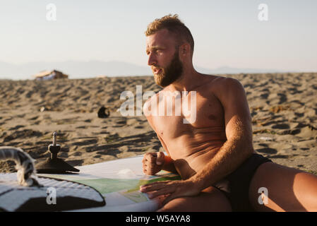 Retrato del hombre que confía con tablas de surf en la playa