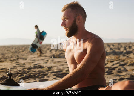 Retrato del hombre que confía con tablas de surf en la playa