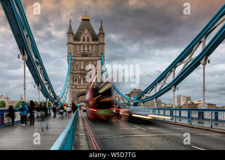 Tower Bridge en Londres, Reino Unido en velada con Moving red doble decker bus dejando rastros de luz, Reino Unido.