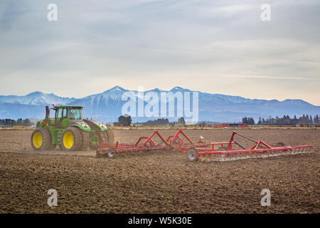Sheffield, Canterbury, Nueva Zelandia, el 27 de julio de 2019: Un gran y moderno tractor John Deere remolca un cultivador en un campo en invierno Foto de stock