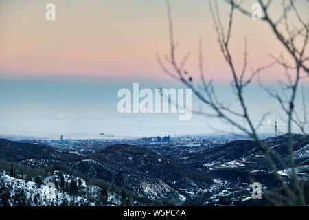 La ciudad de Almaty neblinoso vista desde las montañas en invierno en Kazajstán, Asia Central Foto de stock