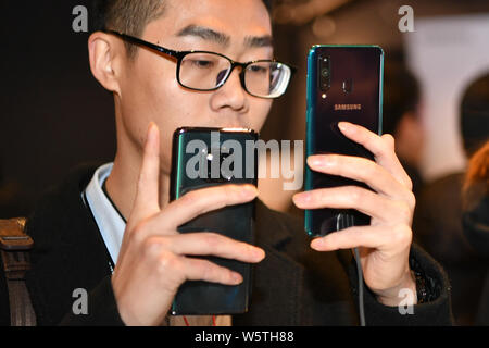 Un cliente intenta un Samsung Galaxy A8s smartphone durante el evento de lanzamiento en Beijing, China, 10 de diciembre de 2018. Samsung anuncia su primer Infini Foto de stock