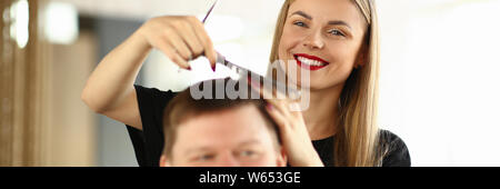 Peluquería peinando el cabello sonriente de cliente masculino Foto de stock