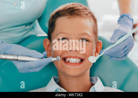 Lindo Niño sonriendo mientras los dientes del examen . Feliz muchacho sentado en la silla de los dentistas y tener dientes check up