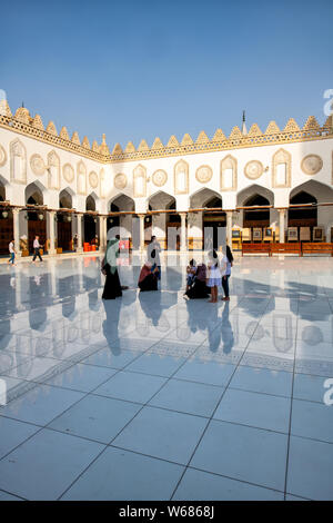 Mujeres y niños caminando por el patio de mármol de la mezquita de Al Azhar de El Cairo Foto de stock