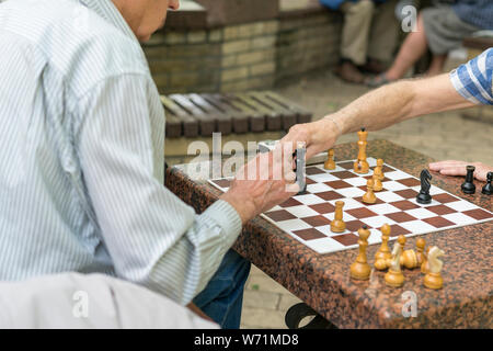 Active los jubilados, viejos amigos y el tiempo libre, los ancianos a divertirse y jugar juego de ajedrez en el parque. Cintura para arriba. Viejos jugando al ajedrez en el parque