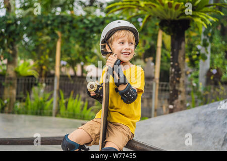 Athletic boy en casco y rodilleras aprende a monopatín en un skate