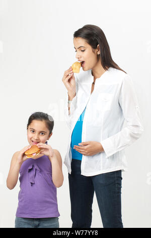 Mujer embarazada y su hija comiendo comida rápida Foto de stock