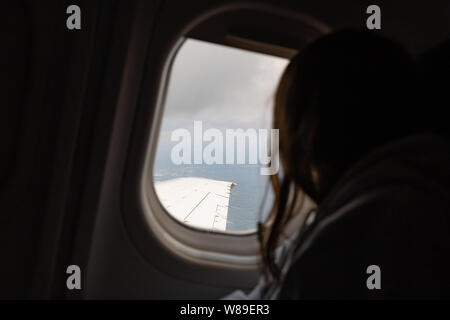 Chica mirando por la ventana del avión en vuelo mientras viaja