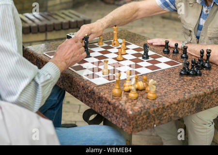 Active los jubilados, viejos amigos y el libre, los ancianos a divertirse y jugar un juego de ajedrez en el parque. Cintura para arriba. Viejos jugando al ajedrez en el parque Fotografía de stock - Alamy