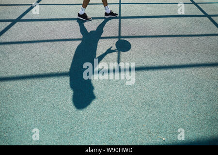 Silueta de hombre irreconocible jugando baloncesto en la corte exterior, antecedentes deportivos, espacio de copia