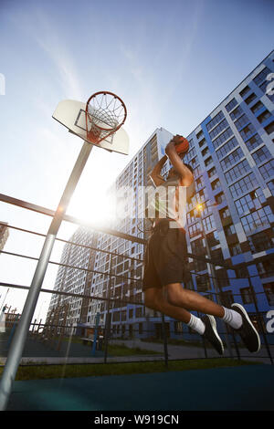 Acción de ángulo bajo foto de jugador de baloncesto africano shooting slam dunk en corte, copie el espacio exterior