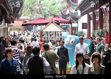 Las multitudes de turistas que caminan más allá de la figura Haibao, la mascota oficial de la Expo Mundial 2010, en el Jardín de Yu en Shanghai, China, 5 de mayo de 2010. Atraer Foto de stock