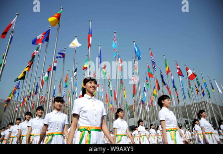 Azafatas chinas pararse junto a banderas nacionales durante la ceremonia de izamiento de la bandera de la Expo de Shanghai, China, 30 de abril de 2010. Shanghai va k Foto de stock