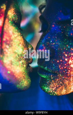 Pareja besándose en la discoteca con pintura fluorescente en la cara Foto de stock