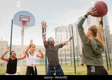 Grupo de estudiantes interculturales o amigos en sportswear jugando baloncesto Foto de stock