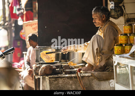 Un anciano indio está cocinando Chapati en las calles de Jaipur. El Chapati es un flatbread sin levadura. Foto de stock